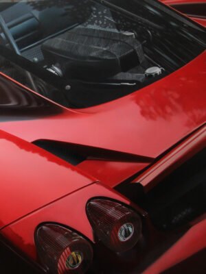 Close-up of a red Ferrari artwork showcasing the rear design and carbon fiber details in artistic style.