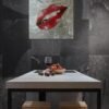 Red lips pop art painting on a textured silver background, displayed on a dark wall above a modern kitchen table.