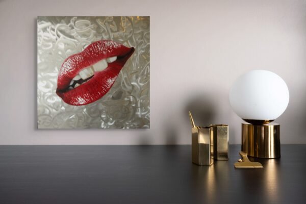 Pop art piece featuring glossy red lips against a textured silver background, displayed on a modern wall.