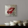 Red lips pop art painting on a textured silver background displayed above a dining setup with roses and ceramic dishes.