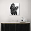 A black-and-white figurative painting depicting an intimate embrace, showcased above a sleek modern console with minimalist decor.