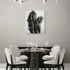 Black-and-white figurative painting of an embrace displayed in a modern dining room with minimalist decor and contemporary chandelier lighting.